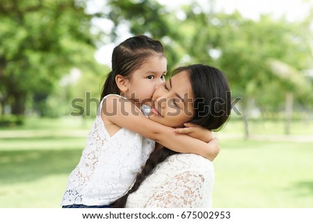 Cute little mixed-race girl kissing her mother on cheek