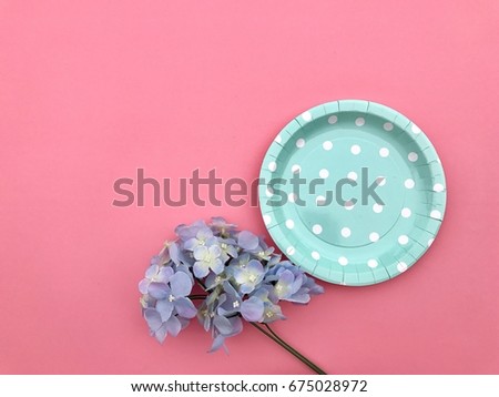 Closeup A light blue polka dot paper plate with A bunch of purple hydrangea flowers set on pale pink background. Top view with Copy space. Selective focus.