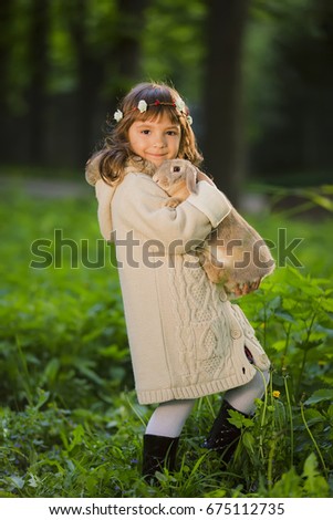 A cute pretty girl in a wreath with a rabbit in the forest. Easter. Spring.