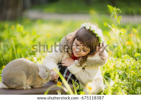 A cute pretty girl in a wreath with a rabbit in the forest. Easter. Spring.