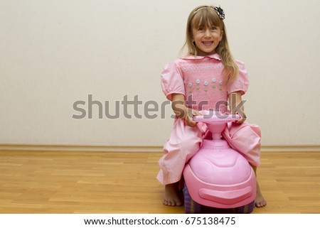 Little Girl in a pink dress on a baby car