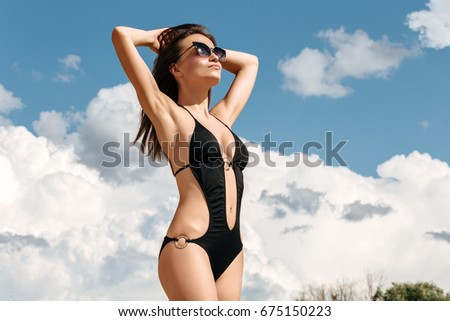 Portrait of beautiful young woman on the beach vacation having fun. Female model wearing bikini standing on the sea shore.