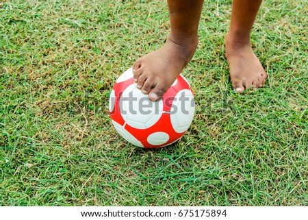 Close up picture of a ball and bare foot of a boy who is playing football