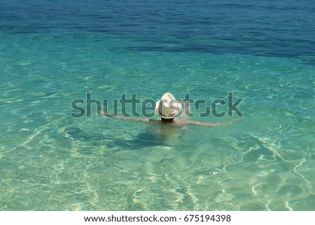 Young girl with white hat enjoying life in tropical ocean.