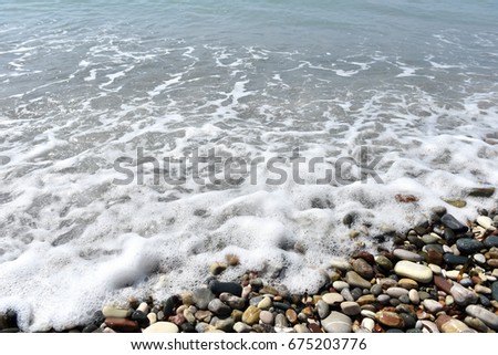 Sea waves approaching pebble stones on the beach