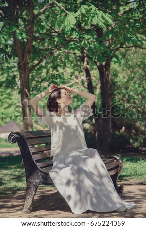 Beautiful girl is sitting on a park bench