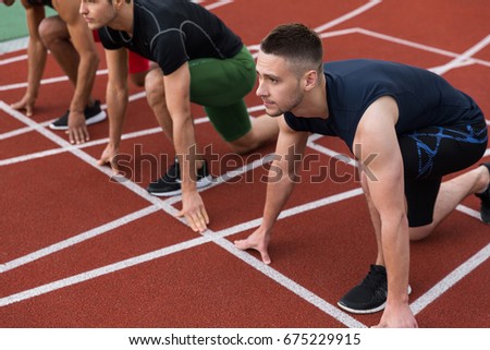 Picture of multiethnic athlete group ready to run on running track outdoors. Looking aside.