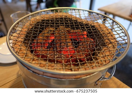 Selective focus at the empty grates on charcoal grill with fire stand on wooden table, preparing for BBQ in local asia street food