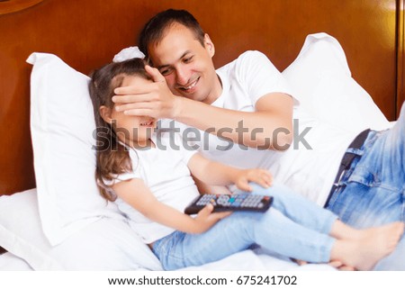 Father and his daughter watching TV.