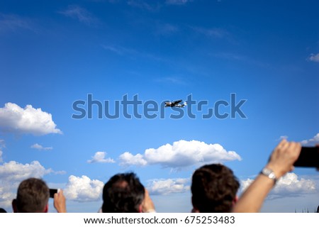 people take photos of jet in the sky at the airshow with their smartphones