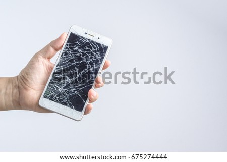 Hand holding mobile phone with broken screen on white background