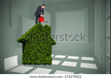 Mature businessman using watering can against white room with squares at wall