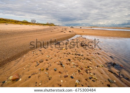 Stone on the sand beach at the coast of sea water in autumn day light