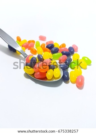 colorful candy in the stainless spoon and white background.