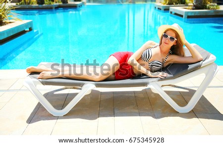 summer holidays concept - pretty woman lying on a deck chair over a blue water pool background