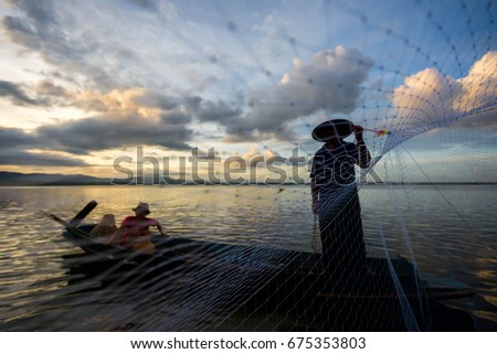 Silhouette of Fisherman of lake in action when fishing on twilight,Thailand