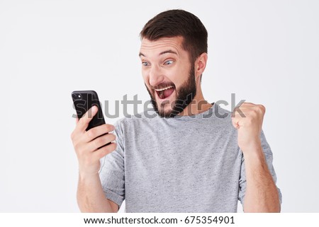 Close-up shot of excited young man screaming on his mobile phone over white background