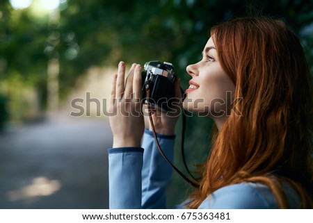 Beautiful young woman taking pictures at the camera on the street.