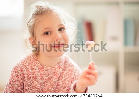 Portrait of pretty happy child girl with lollipop in her hand