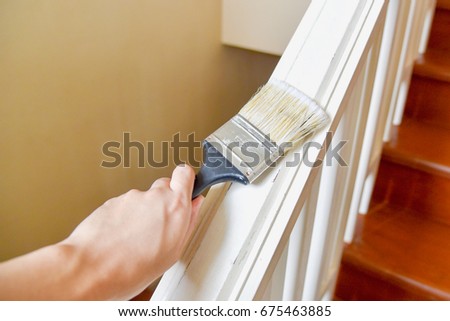 Hand Holding Paint Brush and Painting Stair Handrails with White Color Royalty-Free Stock Photo #675463885