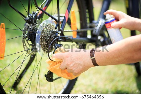 Senior man hands cleaning the bike by spray and rag, doing maintenance