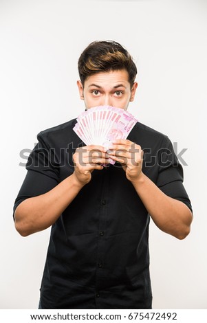 Handsome Indian/Asian man holding Paper currency FAN of Rupees 500 OR 2000, standing isolated over white background