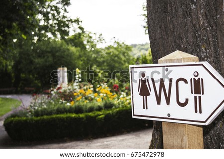 A sign of WC in a garden.