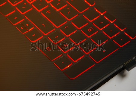 Closeup. Red backlight, backlit on laptop or Computer keyboard. Computer laptop keyboard with red dark backlight, backlit in the dark on the black background. Computer keyboard to the new year 2018