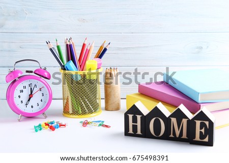 Stationery with alarm clock and books on wooden table