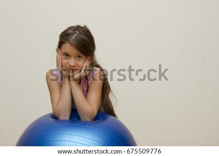 Sporting young girl jumping on a fitball and smiling on a Light background