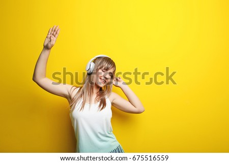 Portrait of young woman with headphones on yellow background
