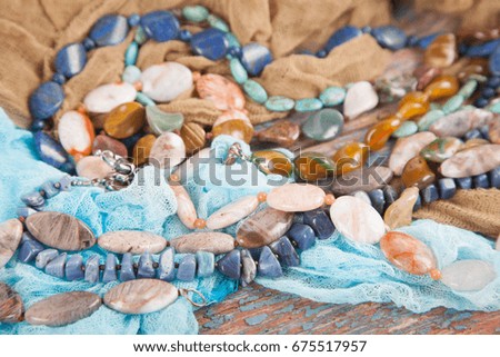 Multicolored beads and necklaces of semi-precious stones on an old wooden background. Women's jewelry