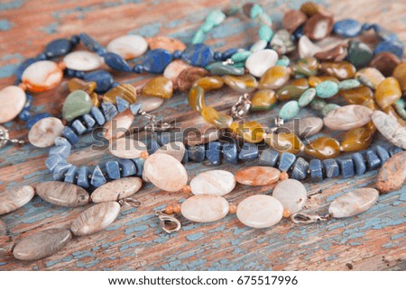 Multicolored beads and necklaces of semi-precious stones on an old wooden background. Women's jewelry