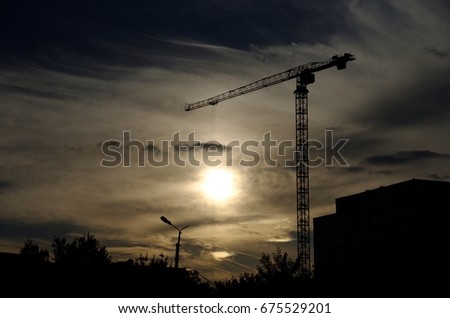 Tower crane against sunset. Overheating economics concept.