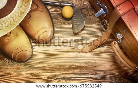 Shoes, straw hat, golf ball on the wooden background