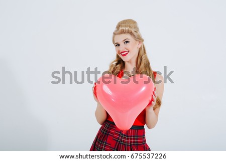 Smiling woman in pin-up style dress, showing blank signboard with copyspace, on grey background. Caucasian blond model posing in retro fashion and vintage concept studio shoot. Banner composition.