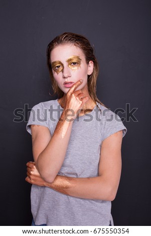 concept creative make-up with use of glitter and paint, which shimmers in different colors. a slender, young woman posing in photo Studio. emotional portrait