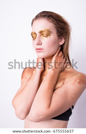 concept creative make-up with use of glitter and paint, which shimmers in different colors. a slender, young woman posing in photo Studio. emotional portrait. athletic body