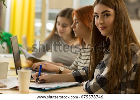 Attractive young businesswoman smiling to the camera while sitting at the boardroom with her female colleagues working on the laptop copyspace productivity creativity teamwork meeting