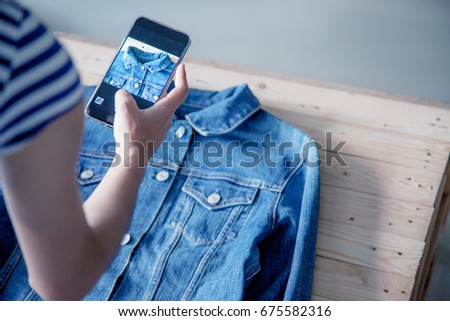 young Women taking photo to shirts with cell telephone or smartphone digital camera for Post to sell Online on the Internet .