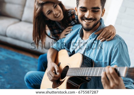Young handsome man playing guitar for his girlfriend
