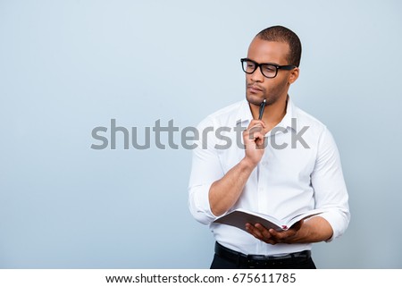 Idea imagination and inspiration concept. Nerdy academic african professor is thoughtful, in glasses, holding a notebook and thinking about exams