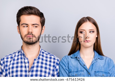 Mistrust and cheat problems. Annoyed couple is ignoring each other, but spy each other secretly, they stand on pure background in casual shirts Royalty-Free Stock Photo #675613426