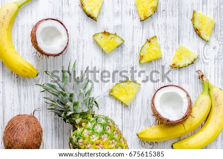 Concept of summer tropical fruits. Pineapple, banana, cocount on wooden background top view copyspace