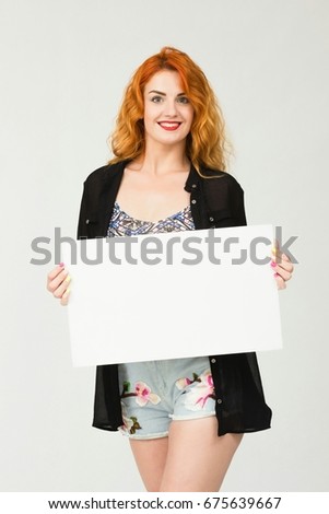 Portrait young Red-haired girl in casual clothes holding a white blank banner.