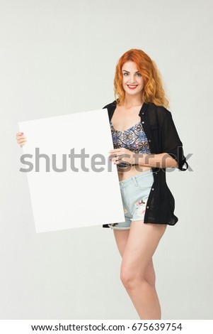 Portrait young Red-haired girl in casual clothes holding a white blank banner.