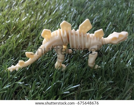 A Dinosaur Skeleton Model Toy On A Green Grass.