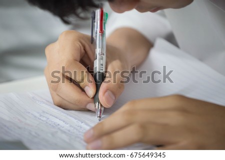 soft focus.university or high school student holding pencil.sitting on row chair writing final exam in examination room or study in classroom.student in uniform.space for text.education concept