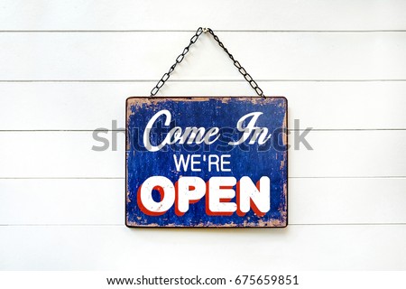 Welcome Sign with text "COME IN WE'RE OPEN' hanging on wood white wall