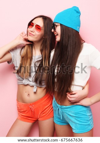 happy smiling pretty teenage girls or friends hugging over pink background.